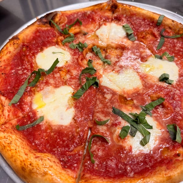 A freshly baked Margherita pizza with bright red sauce, melted mozzarella, and fresh basil leaves.