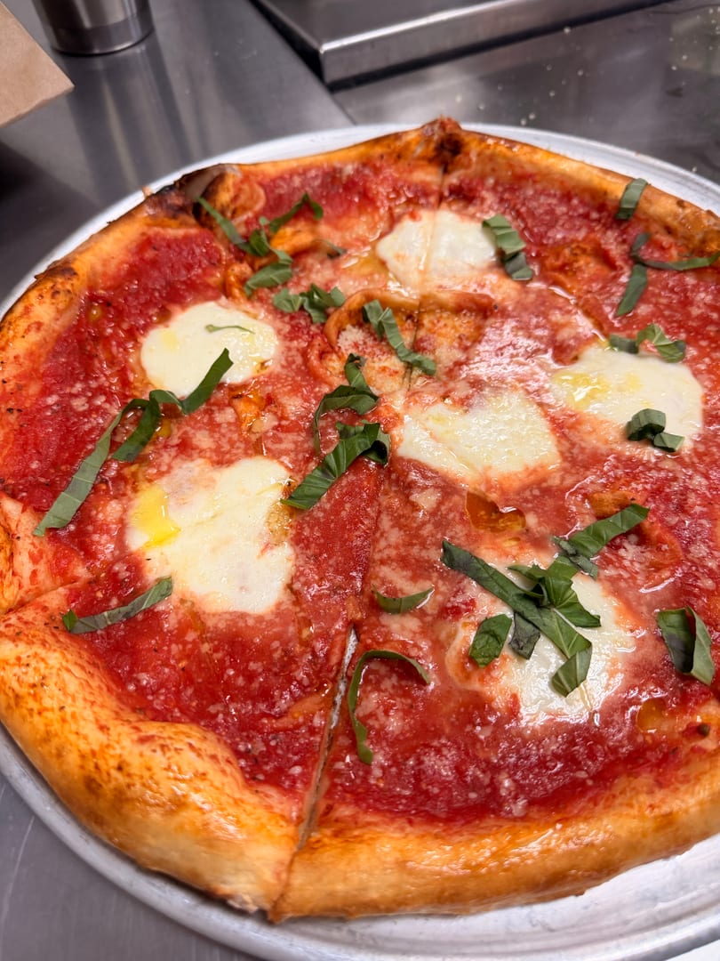 A freshly baked Margherita pizza with bright red sauce, melted mozzarella, and fresh basil leaves.