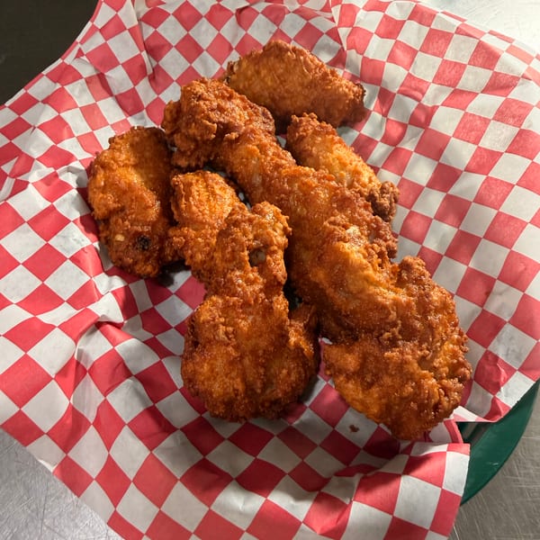 Crispy fried chicken pieces served in a red and white checkered paper-lined basket.