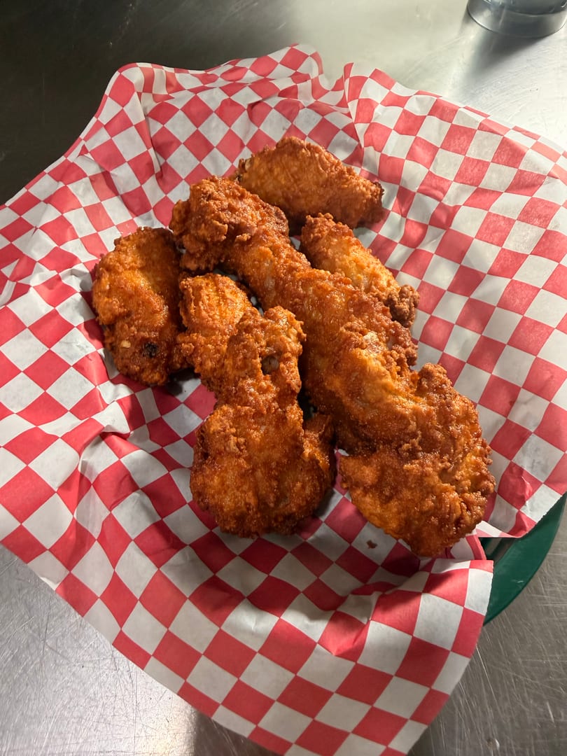 Crispy fried chicken pieces served in a red and white checkered paper-lined basket.